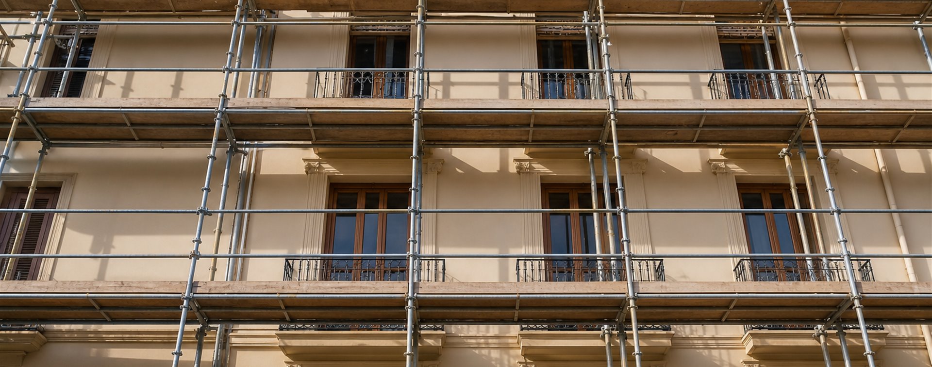 Empty metal scaffolding covering a cream Valencia apartment facade under renovation