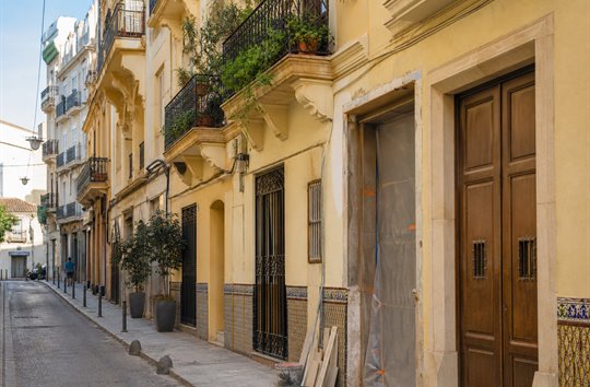 Sunlit Valencia street with tiled façades and wrought-iron balconies