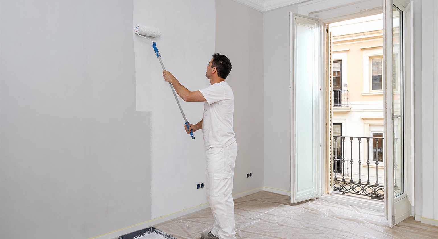 Painter rolling fresh emulsion onto prepared interior walls